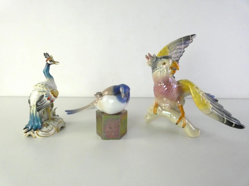 Drie kleurrijke keramische vogelbeeldjes.